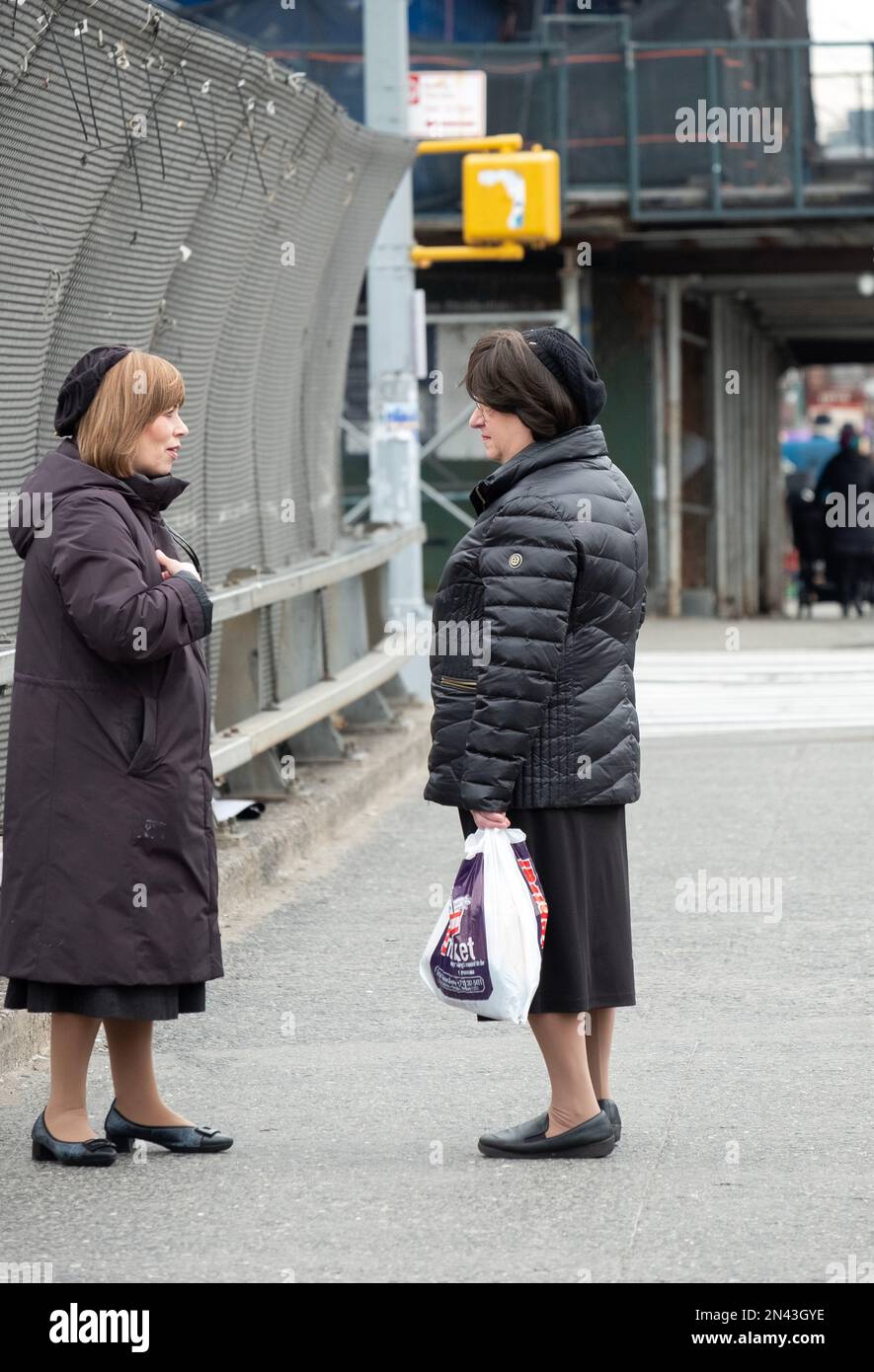 2 Hasidic Jewish women, modestly dressed & wearing a very similar hat, have a chat . In New ork City. Stock Photo