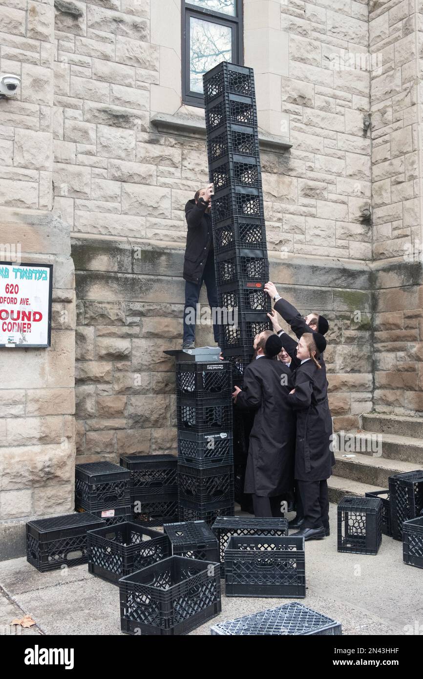 Ultra orthodox Jewish yeshiva students at an urban school build a tower out of milk crates during their recess. In New York City. Stock Photo