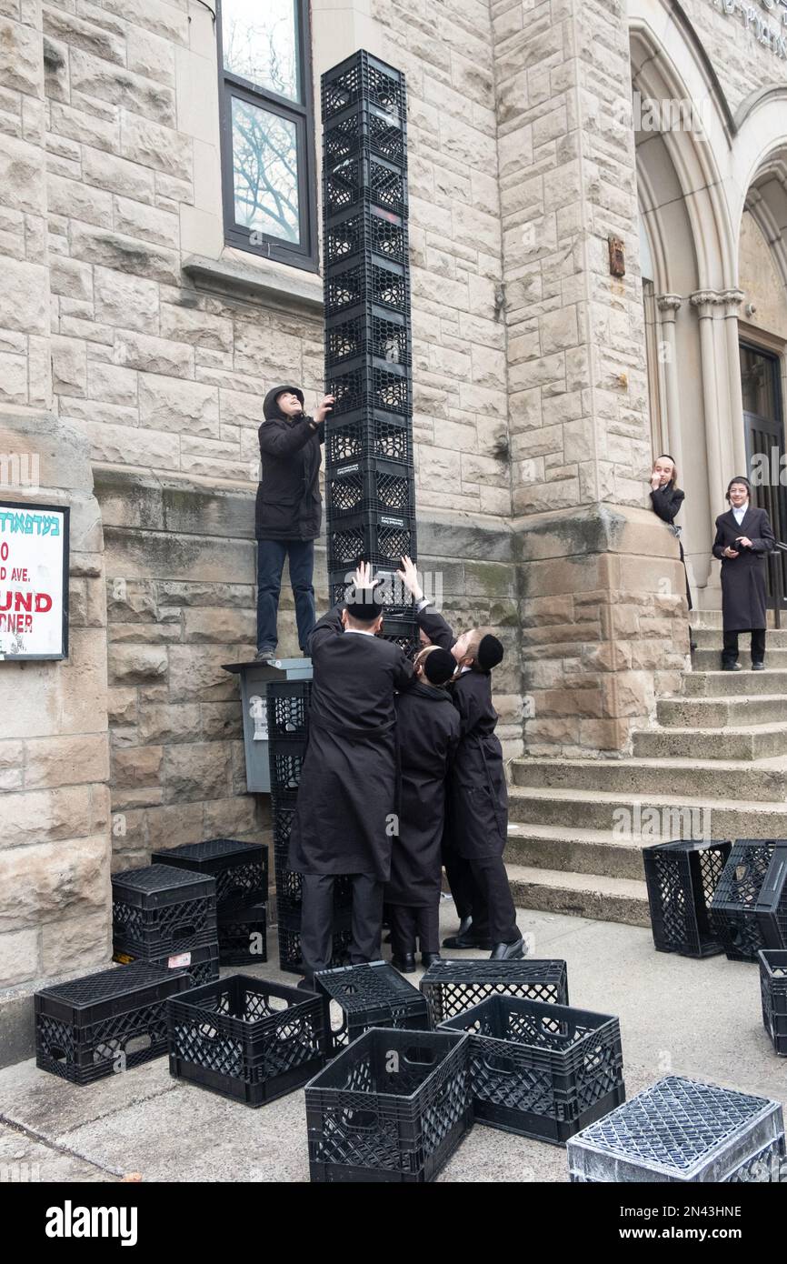 Ultra orthodox Jewish yeshiva students at an urban school spend recess  building a tower out of milk crates on a sidewalk. In New York City. Stock Photo