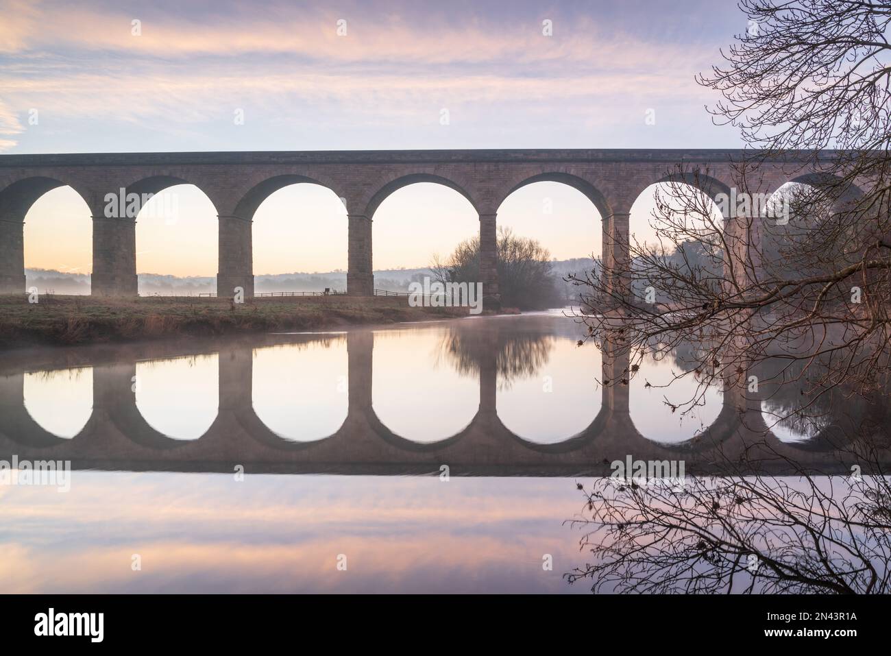 The arches of Arthington Viaduct in the Lower Wharfe Valley are reflected in the River Wharfe on a beautiful winter morning in early February. Stock Photo
