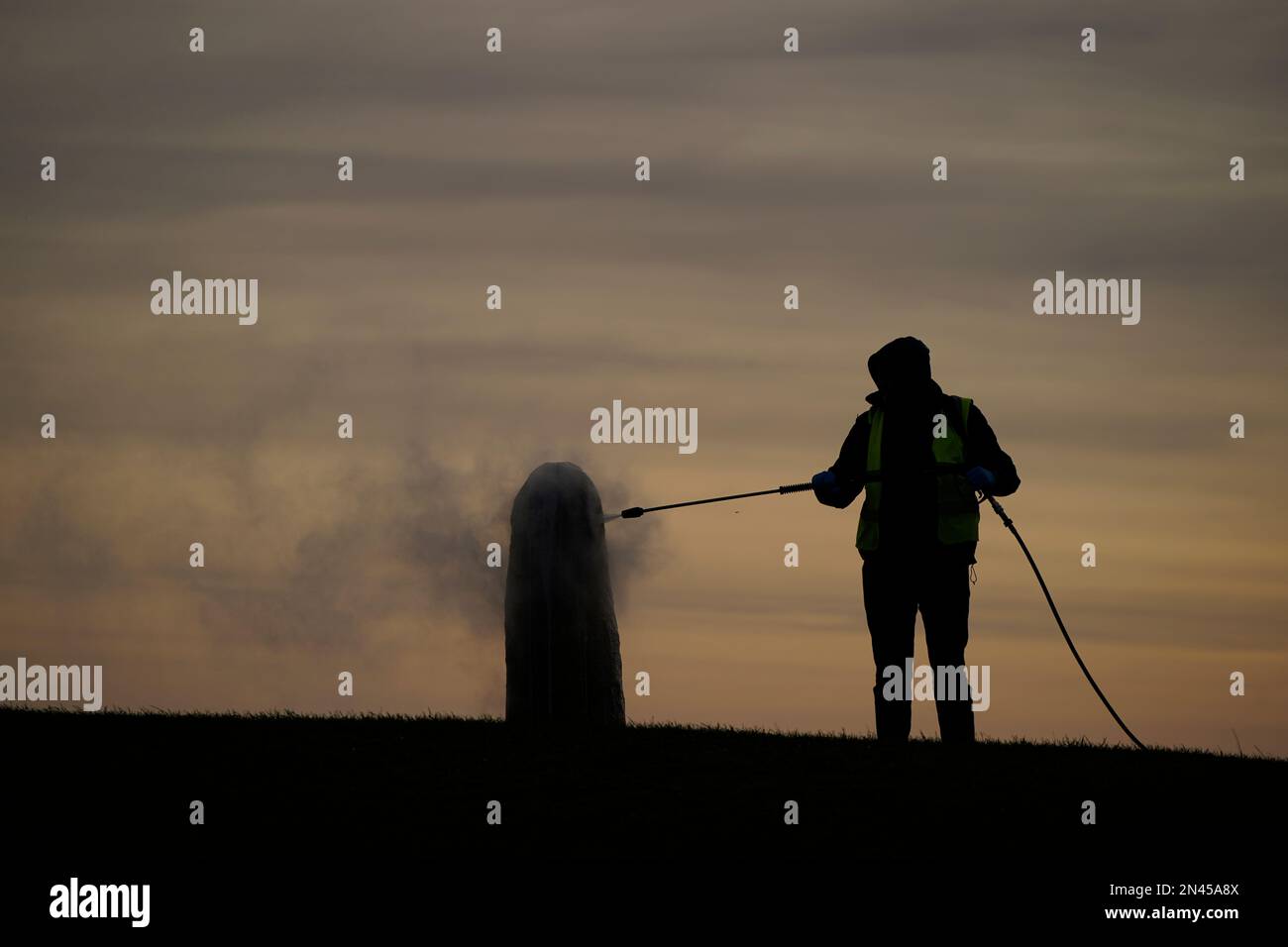 A worker from the office of public works begin the clean up of graffiti on the Lia Fail standing stone, which is also known as the Stone of Destiny, on the Hill of Tara near Skryne in County Meath. Picture date: Wednesday February 8, 2023. Stock Photo