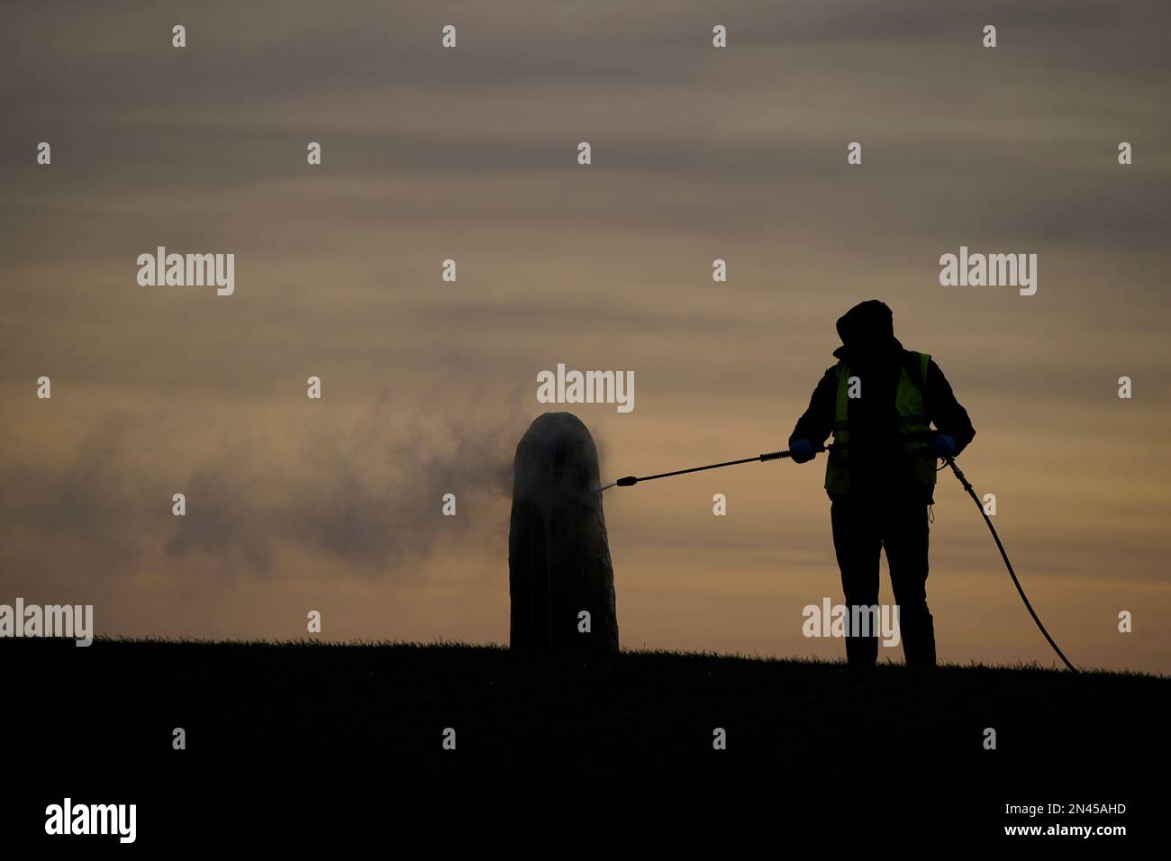 A worker from the office of public works begin the clean up of graffiti on the Lia Fail standing stone, which is also known as the Stone of Destiny, on the Hill of Tara near Skryne in County Meath. Picture date: Wednesday February 8, 2023. Stock Photo