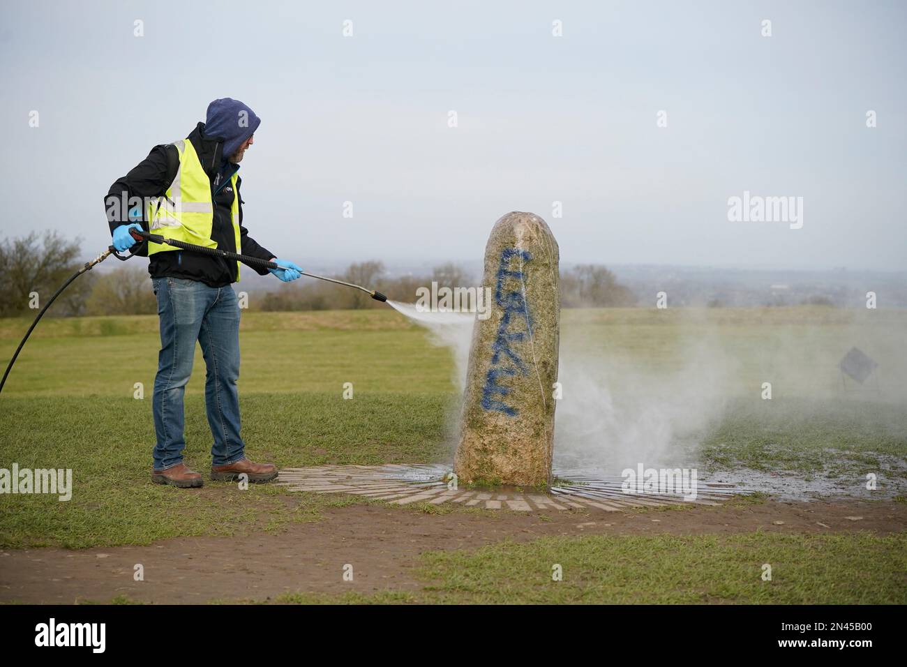 A worker from the office of public works begin the clean up of graffiti on the Lia Fail standing stone, which is also known as the Stone of Destiny, on the Hill of Tara near Skryne in County Meath. Picture date: Wednesday February 8, 2023. Stock Photo