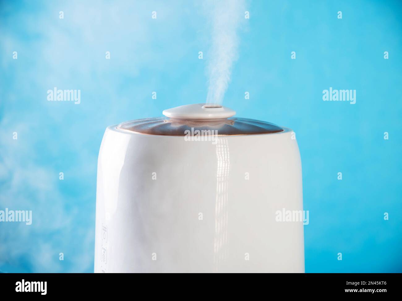 White wet steam from a humidifier on a blue background. Device for