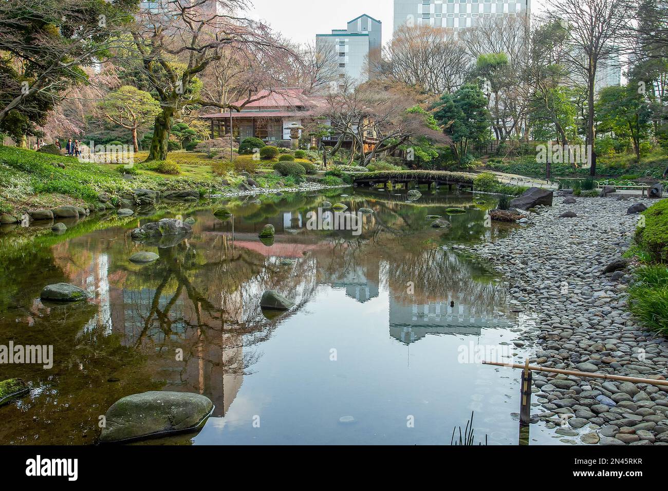 Beautiful Koishikawa Korakuen park a few days before cherry blossoms and hanami (March 22) in Tokyo: a pond and an ancient thatched bridge Stock Photo