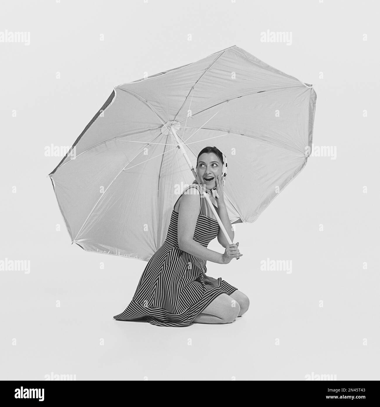Happy excited young beautiful girl sitting under big sun beach umbrella