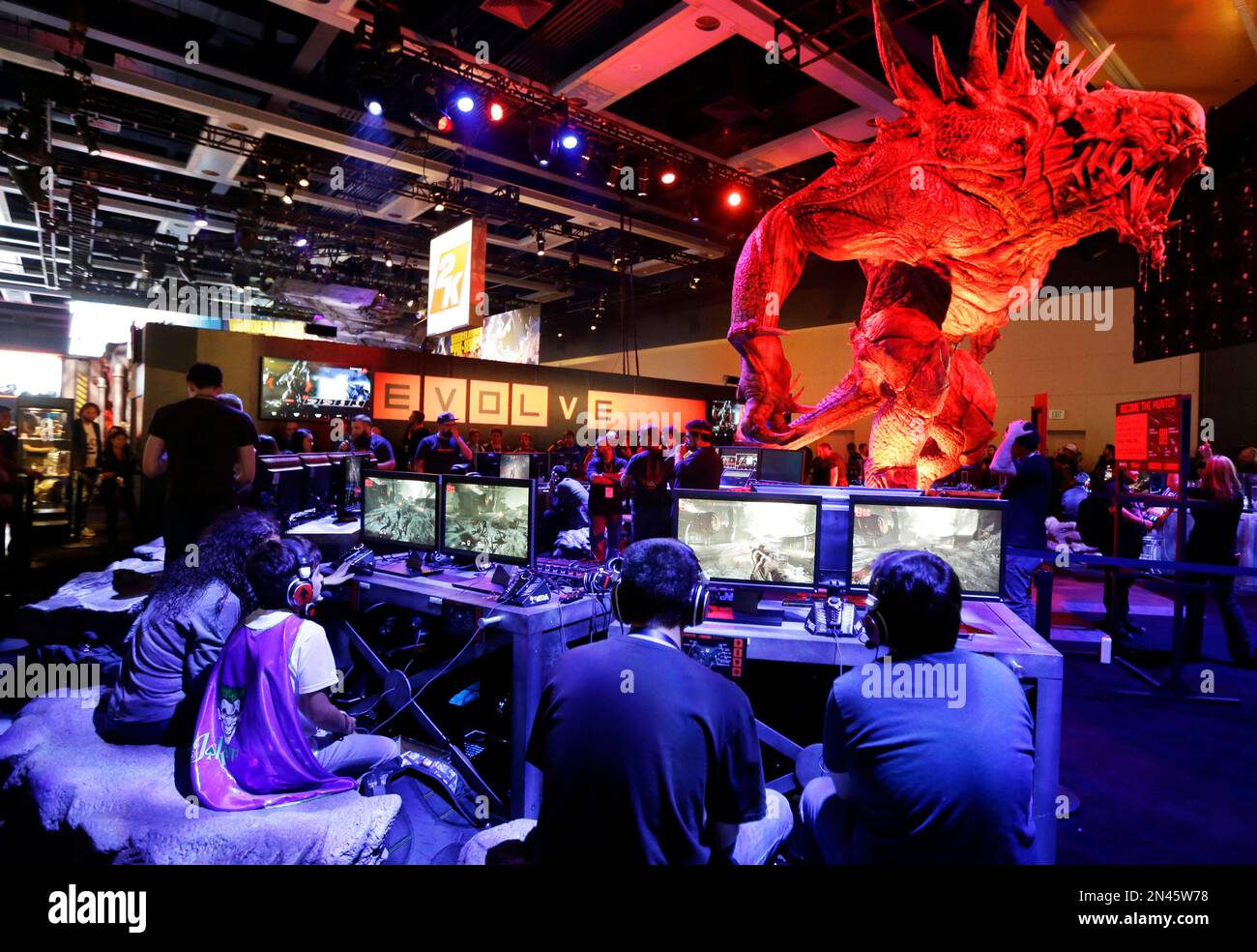 A giant monster looms over gamers playing Evolve, a video game published by  2K Games, which is scheduled to be released in early 2015, Friday, Aug. 29,  2014, at the Penny Arcade, image size:1300x984