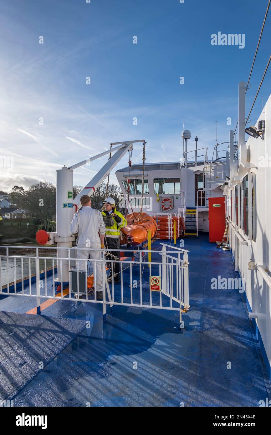 Two Wightlink crew members discussing problem with lifeboat launch crane Saint Faith ferry Fishbourne Isle of Wight 2023 Stock Photo