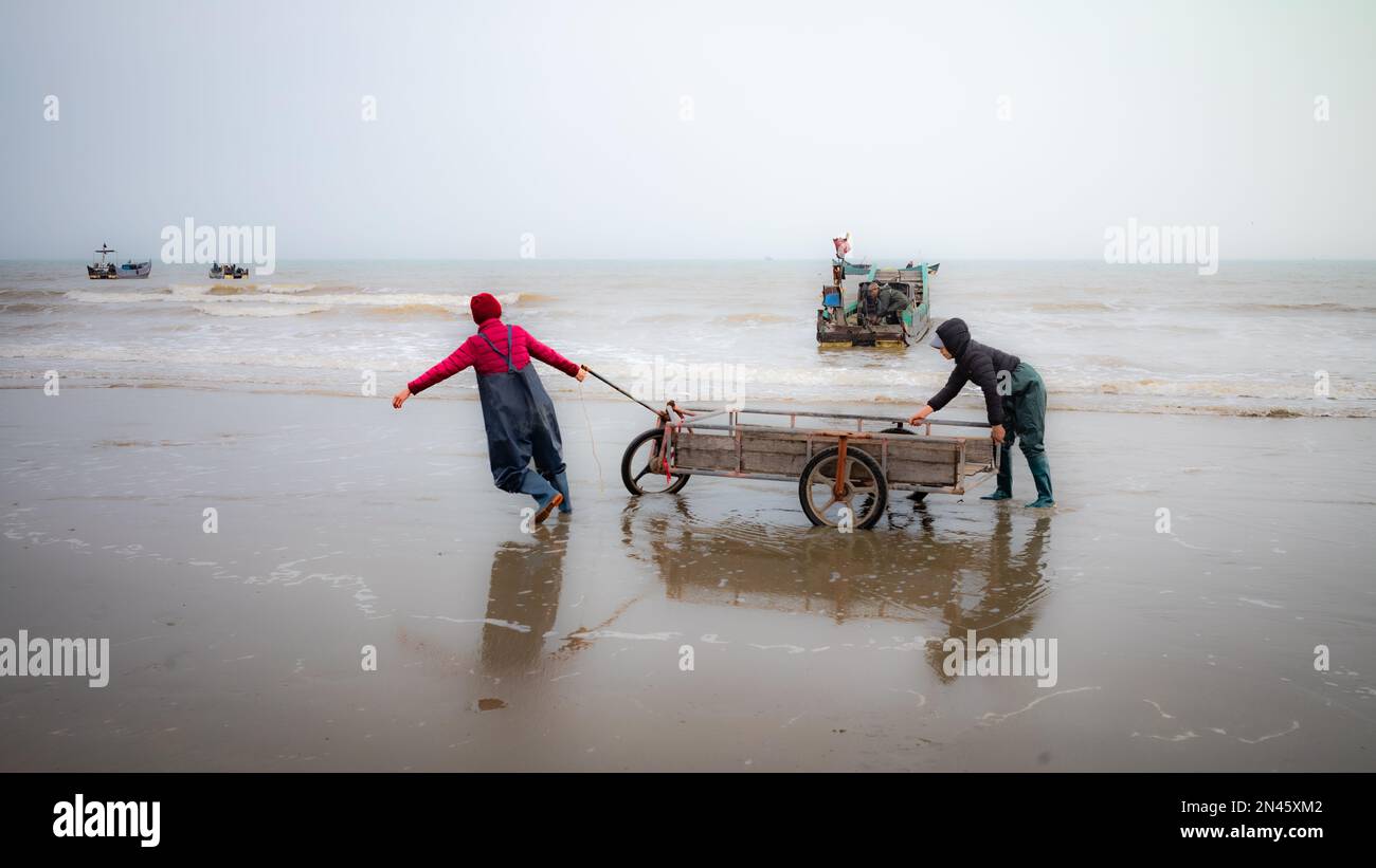Two women try to move a trolley after unloading fishing gear ready