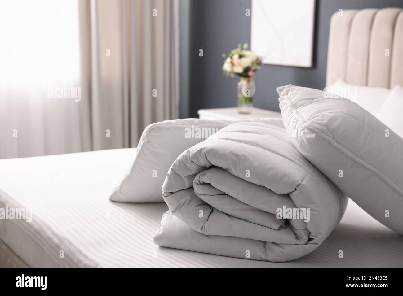 Soft folded blanket and pillows on bed indoors Stock Photo