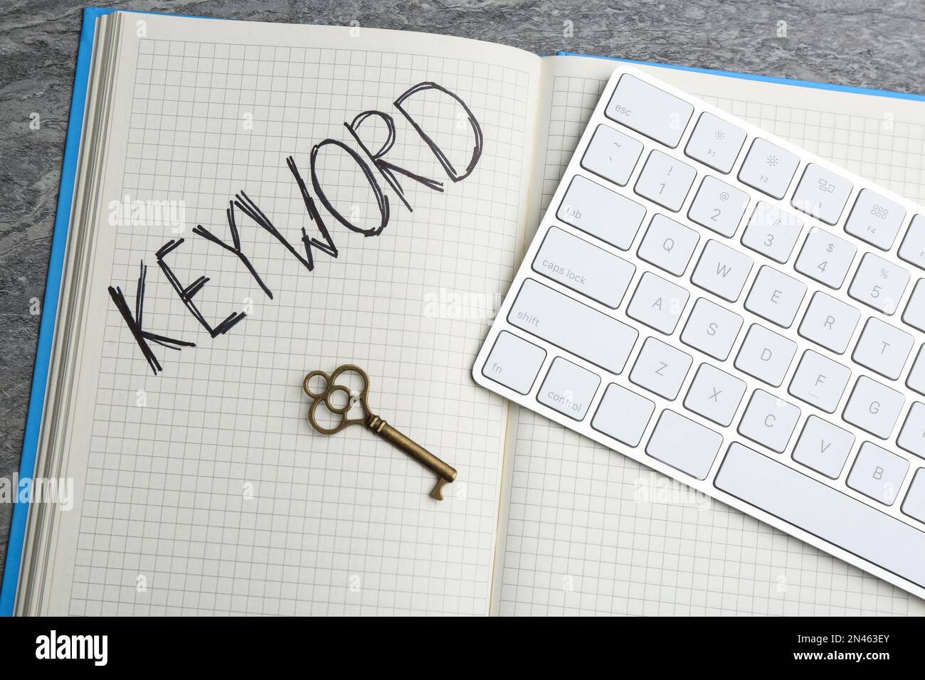 Key, notebook and computer keyboard on table, flat lay. Keyword concept Stock Photo