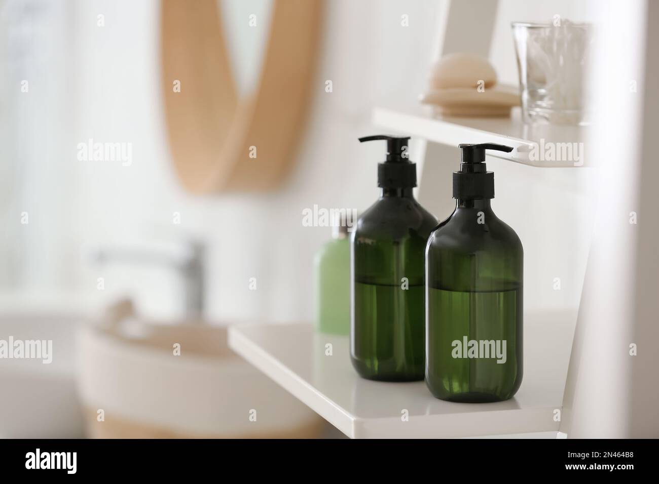 Green soap dispensers on white shelving unit in bathroom. Space for
