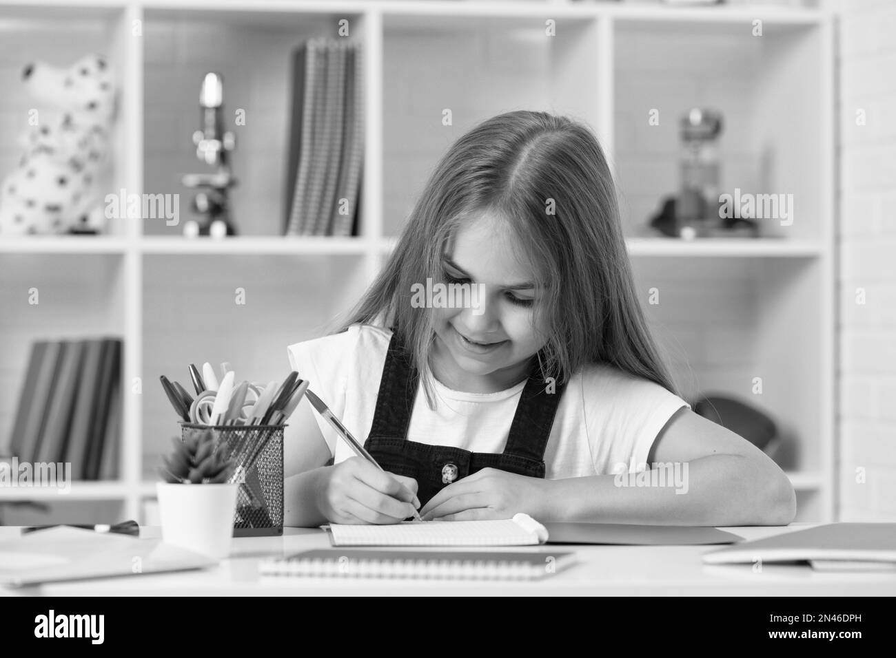 happy kid write in workbook at school lesson in classroom wear uniform, knowledge Stock Photo