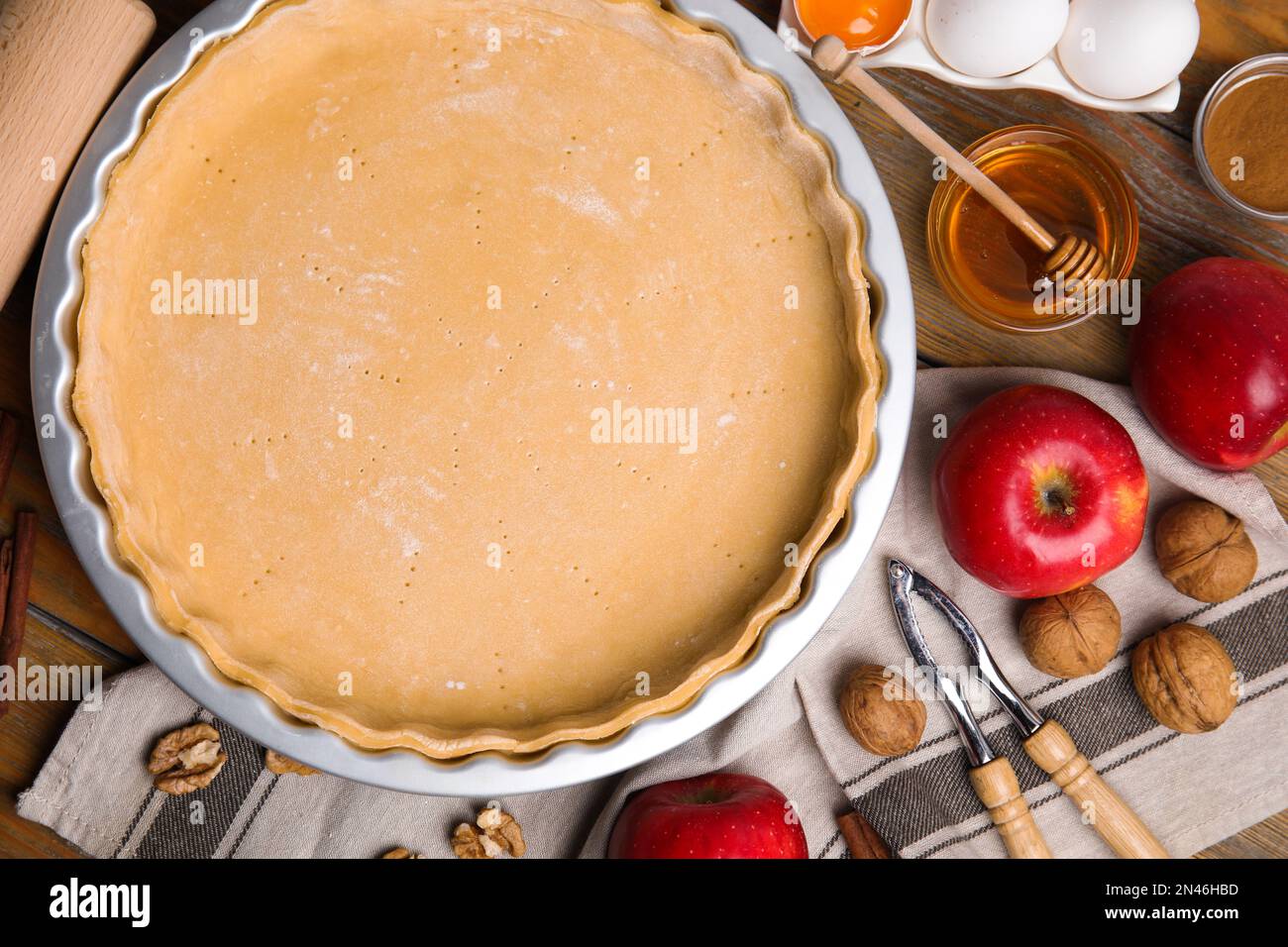Raw dough and ingredients for traditional English apple pie on wooden table, flat lay Stock Photo