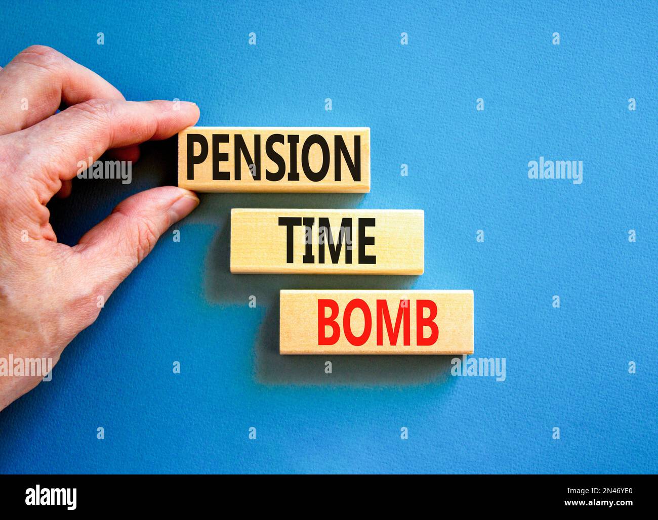 Pension time bomb symbol. Concept words Pension time bomb on wooden blocks on a beautiful blue table blue background. Businessman hand. Business pensi Stock Photo