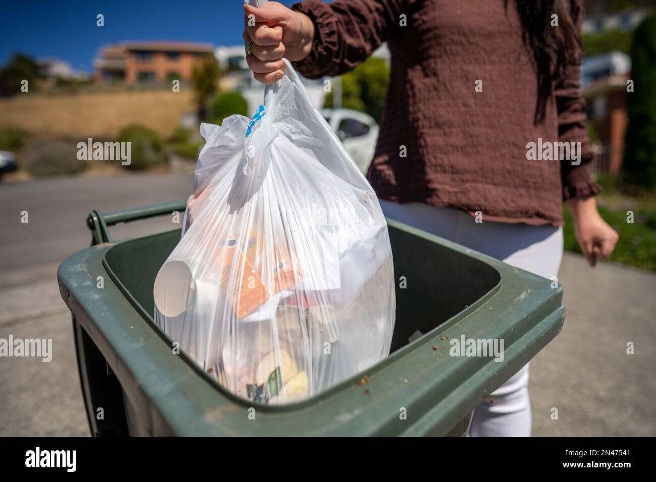 Throwing rubbish in the bin and sorting recycling. Putting rubbish in an inside bin in australia
