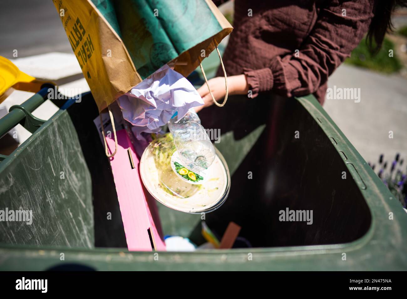 Throwing rubbish in the bin and sorting recycling. Putting rubbish in an inside bin in australia