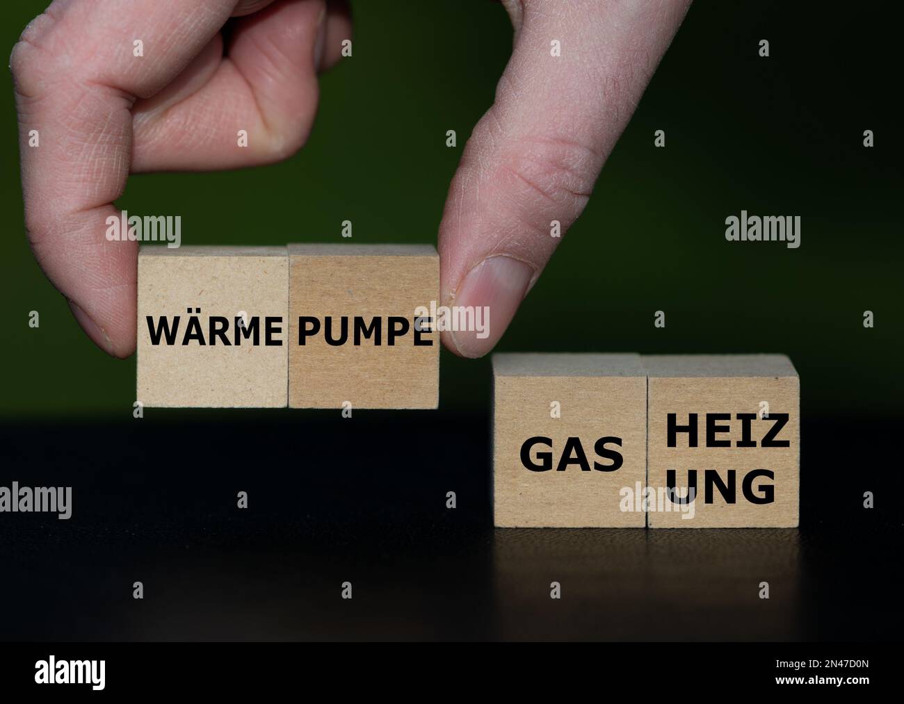 Hand picks cubes with the German text 'Waermepumpe' (heat pump) instead of cubes with the text 'Gas Heizung' (gas heating). Stock Photo