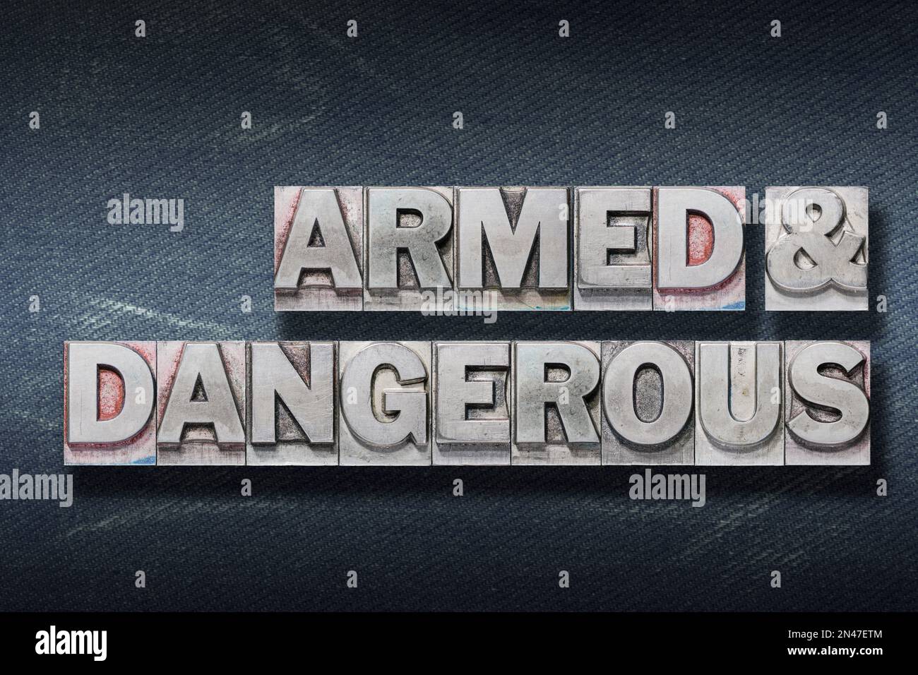armed and dangerous phrase made from metallic letterpress on dark jeans ...
