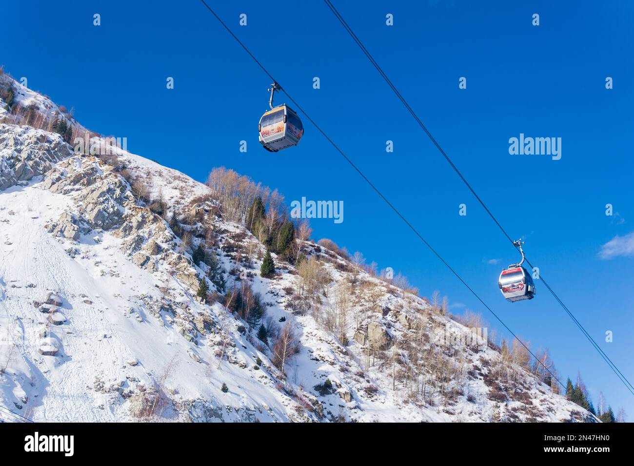 Almaty, Kazakhstan - January 08, 2023: cable cars for skiers against the backdrop of a blue sky and snowy mountain slopes, view from the bottom up Stock Photo