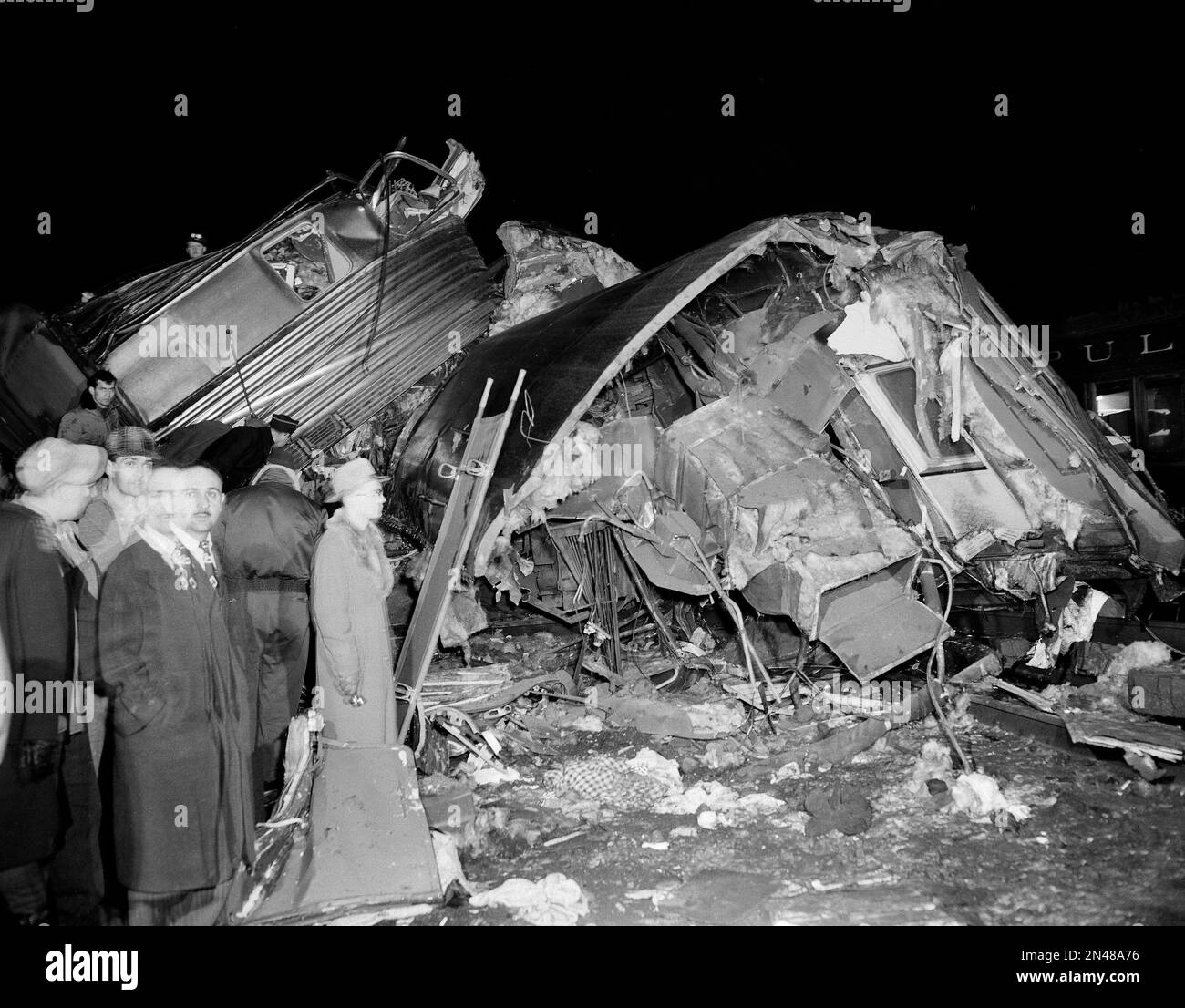 Spectators look at a section of two wrecked coaches of the New York