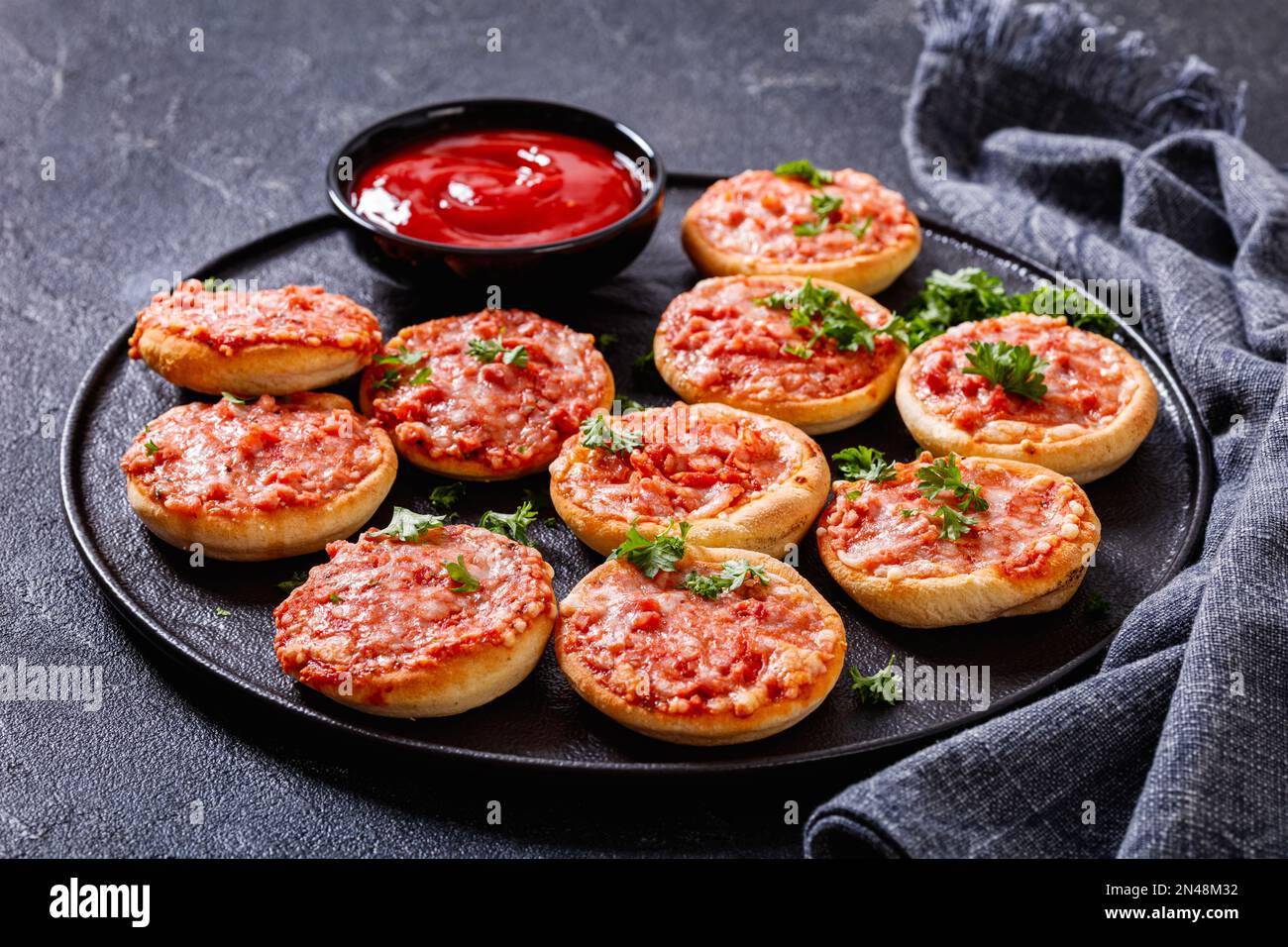 mini pizzas, piccolinis, with ham and pecorino cheese on black plate ...