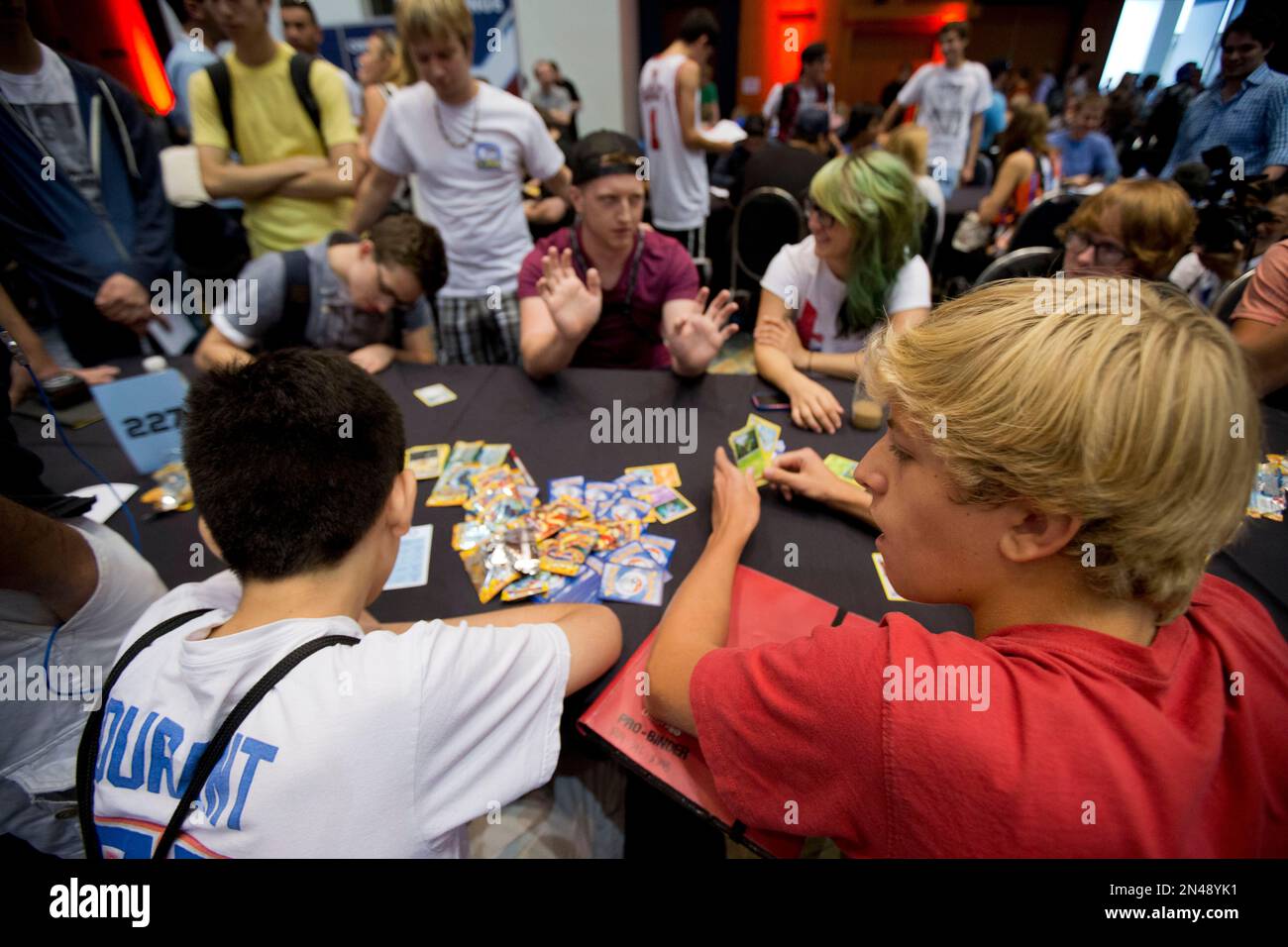 Competitors Henry Ross-Clunis, front right, Kyle Sabelhaus, maroon shirt,  and Nicholena Moon, green hair, trade cards and discuss strategy for a last  chance qualifier spot in the Pokmon trading card game for