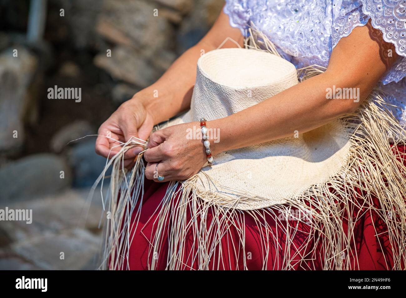 Ecuadorian indigenous chola woman weaving Panama hat from Toquilla palm leaf fiber, Cuenca, Ecuador. Stock Photo