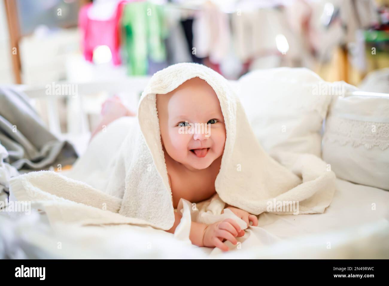 A small newborn baby under a white towel underneath hygiene procedures