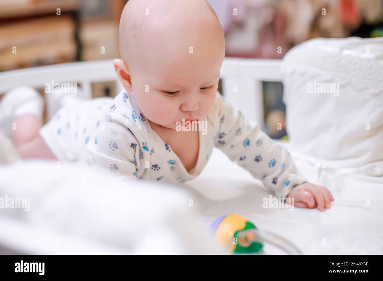 The newborn baby rose on the handles in a crib with a white sheet. The
