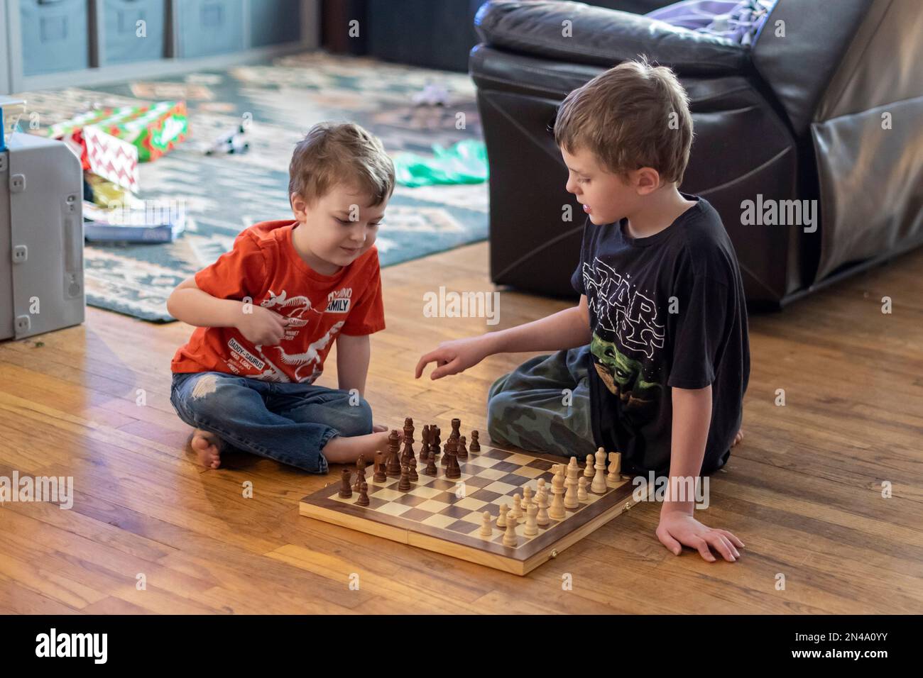 Kids playing chess. Two boys, aged six and eight years, think