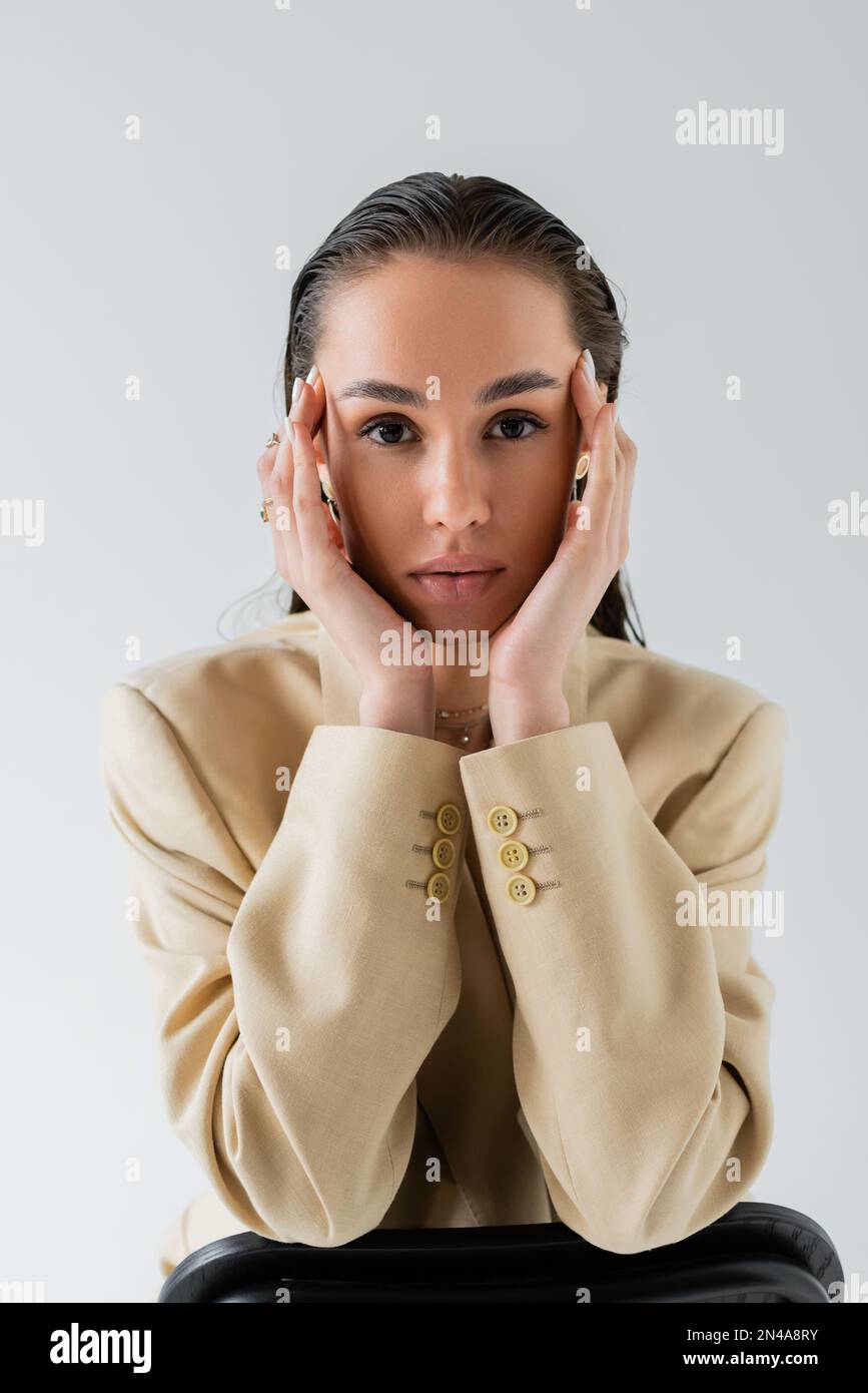 pretty model in beige stylish blazer looking at camera isolated on grey Stock Photo