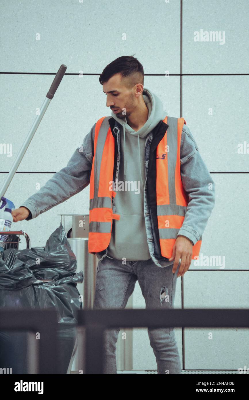 A vertical closeup of a worker cleaning up, putting plastic bottles in a bin Stock Photo