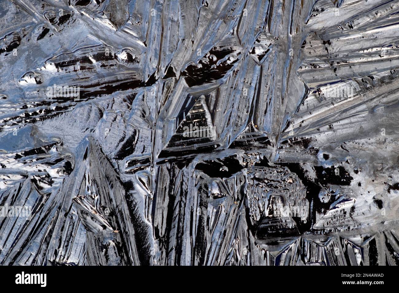 Shards of frozen water ice form patterns look black view from above photographed in a dark opaque container on a freezing cold day UK   KATHY DEWITT Stock Photo