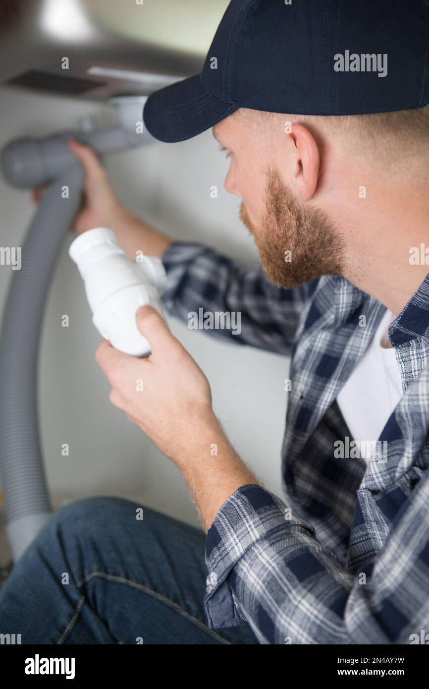 plumber fixes sink siphon by two pipe-wrenches in bathroom Stock Photo