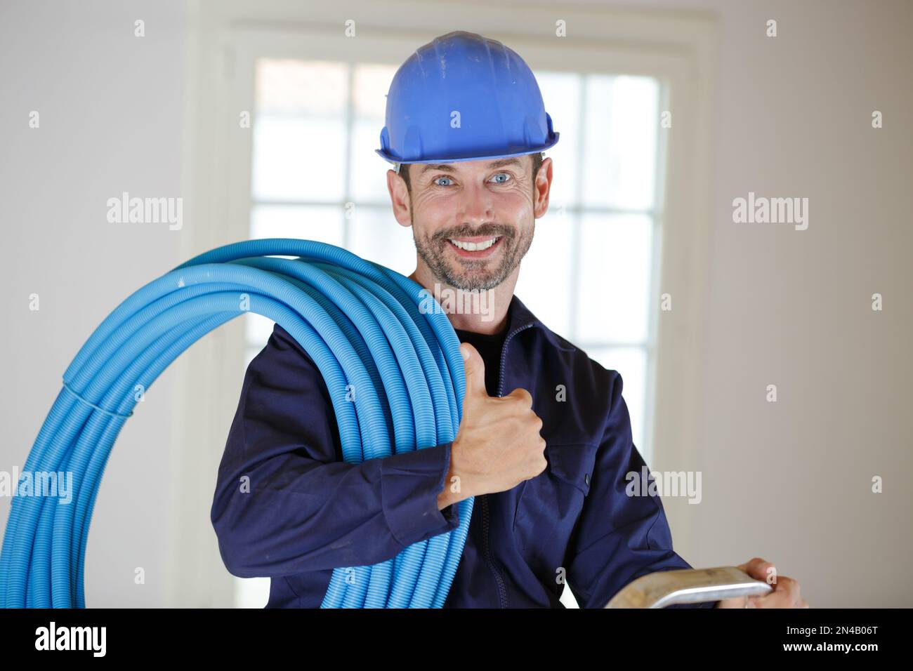 smiling builder indoors holding pipes Stock Photo