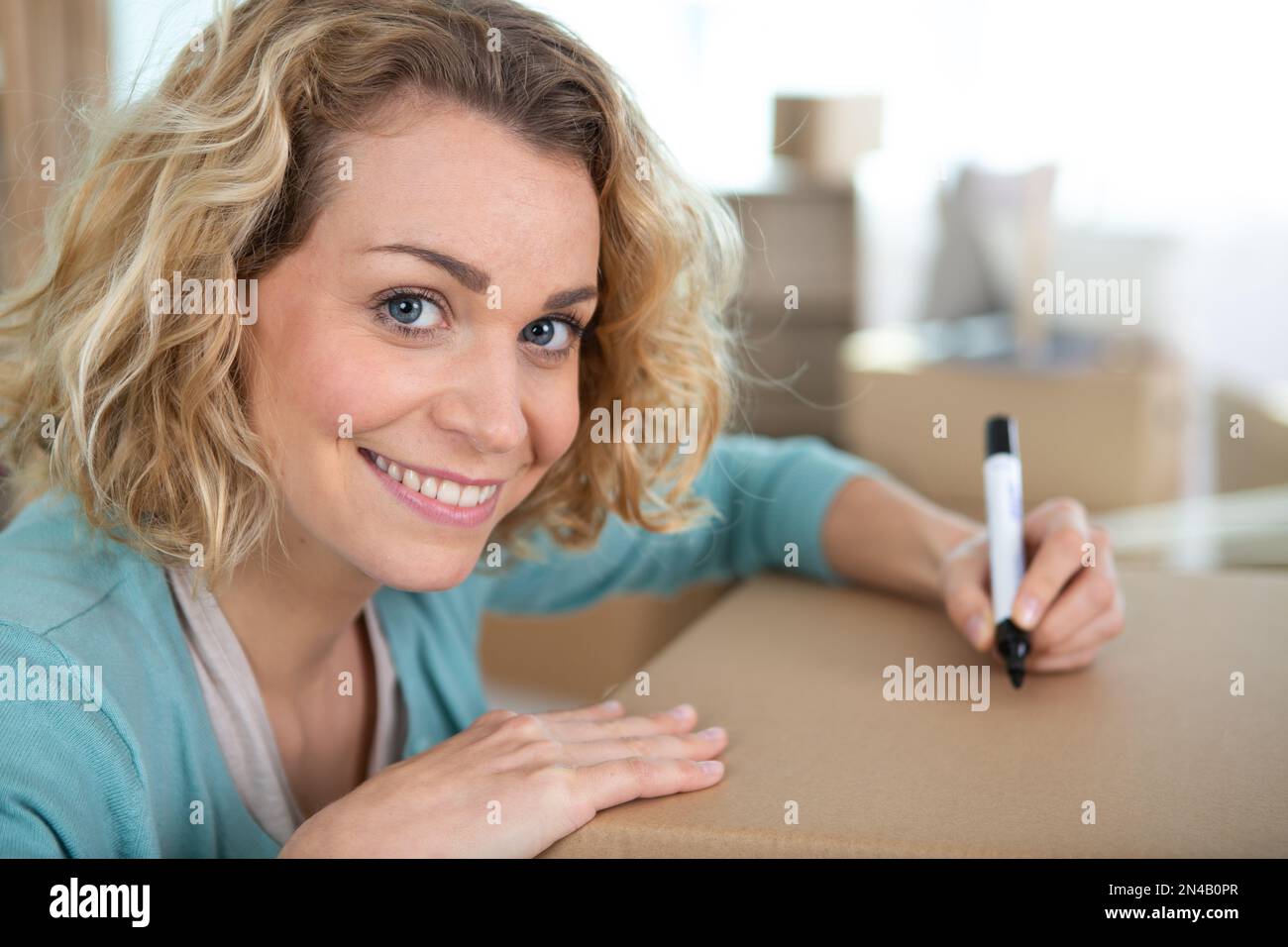 beautiful young woman marking a cardboard box Stock Photo Alamy