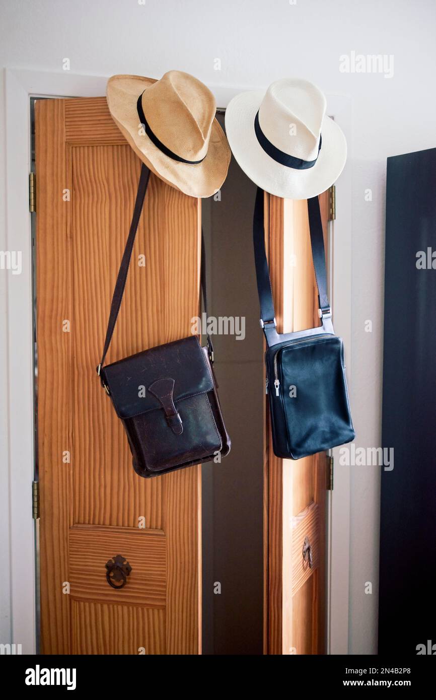 Vertical His and hers straw hats and leather messengerstyle bags