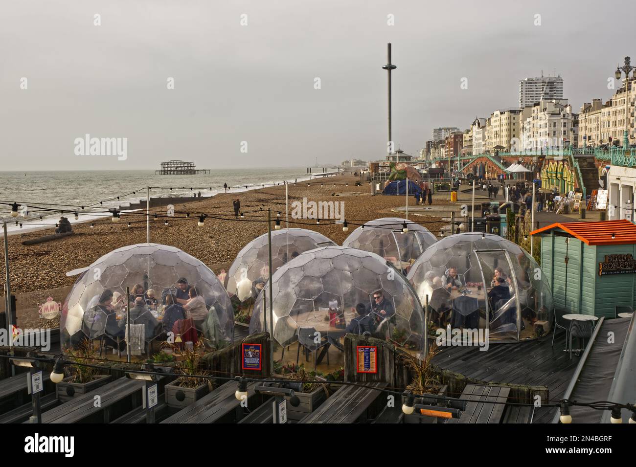 Seafront and beach with restaurant outdoor seating and bubble pods