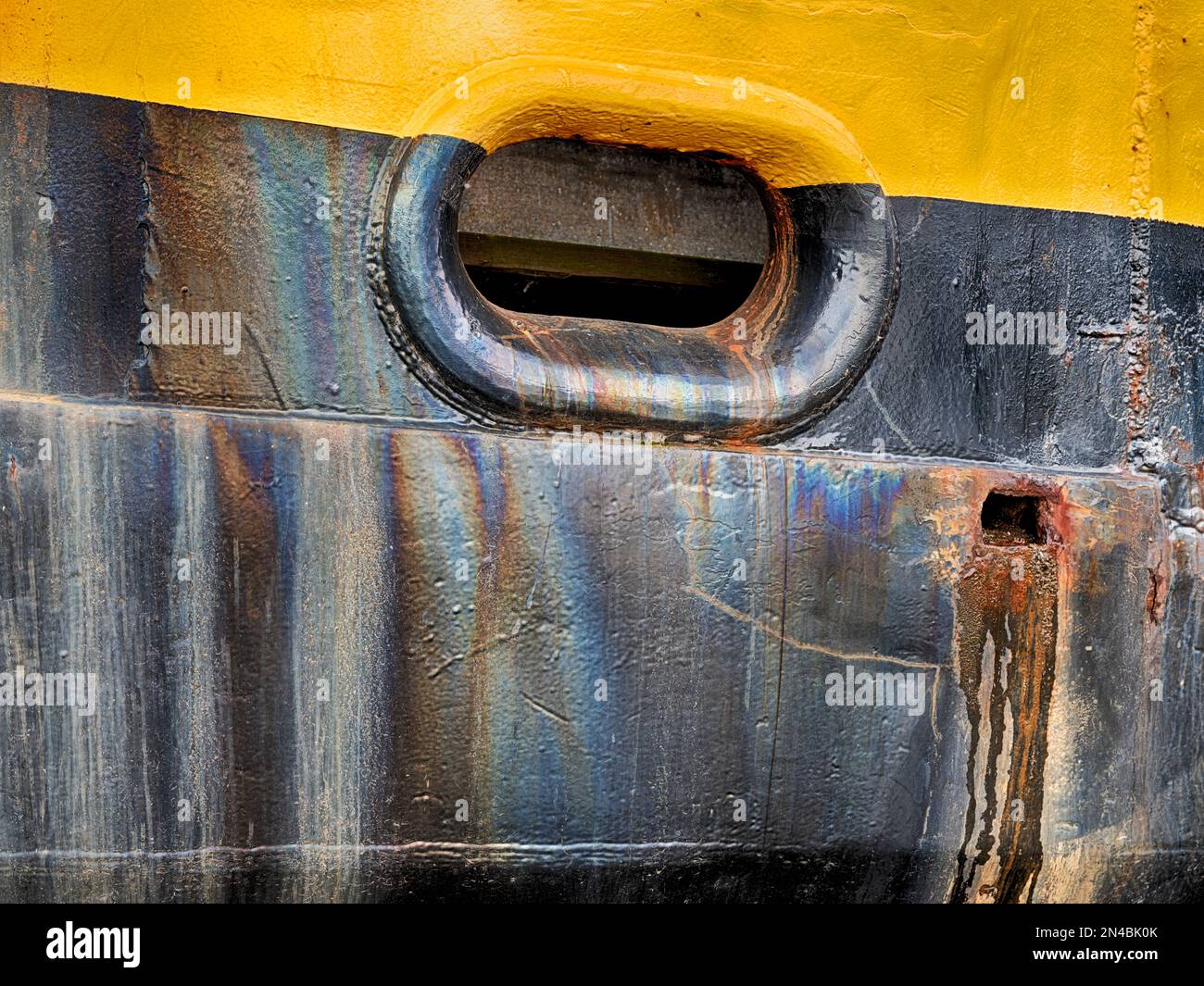 Oil stains provide an oily sheen over the yellow and black hull of a fishing boat in Seattle. Stock Photo