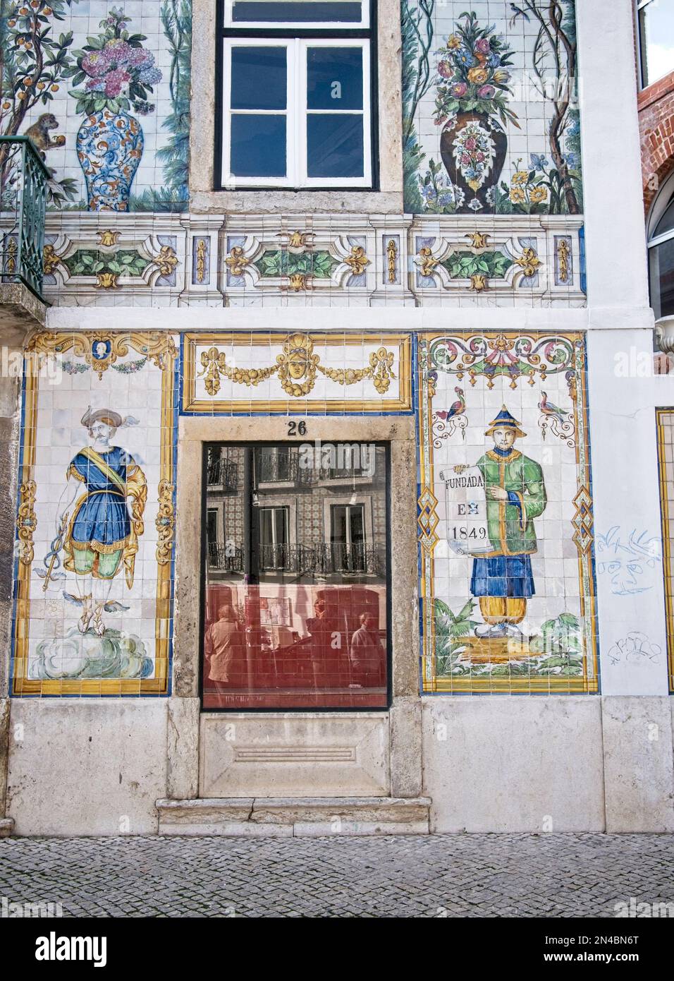 Vertical Elaborate colored tiled artwork on building wall with figures, flowers and vases, and ornate decorations, in Lisbon, Portugal Stock Photo