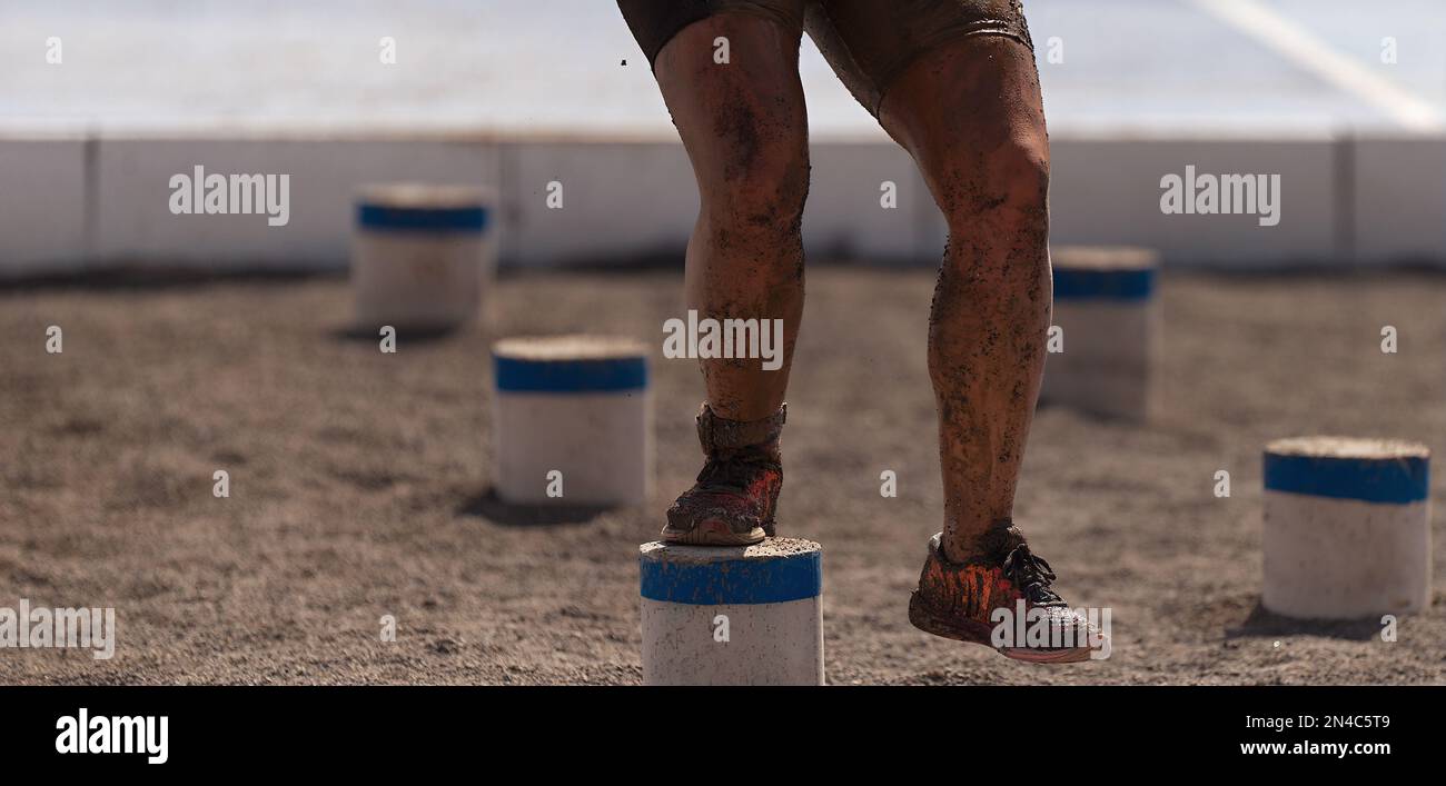 Mud race runners. The participante overcoming the obstacle Stock Photo