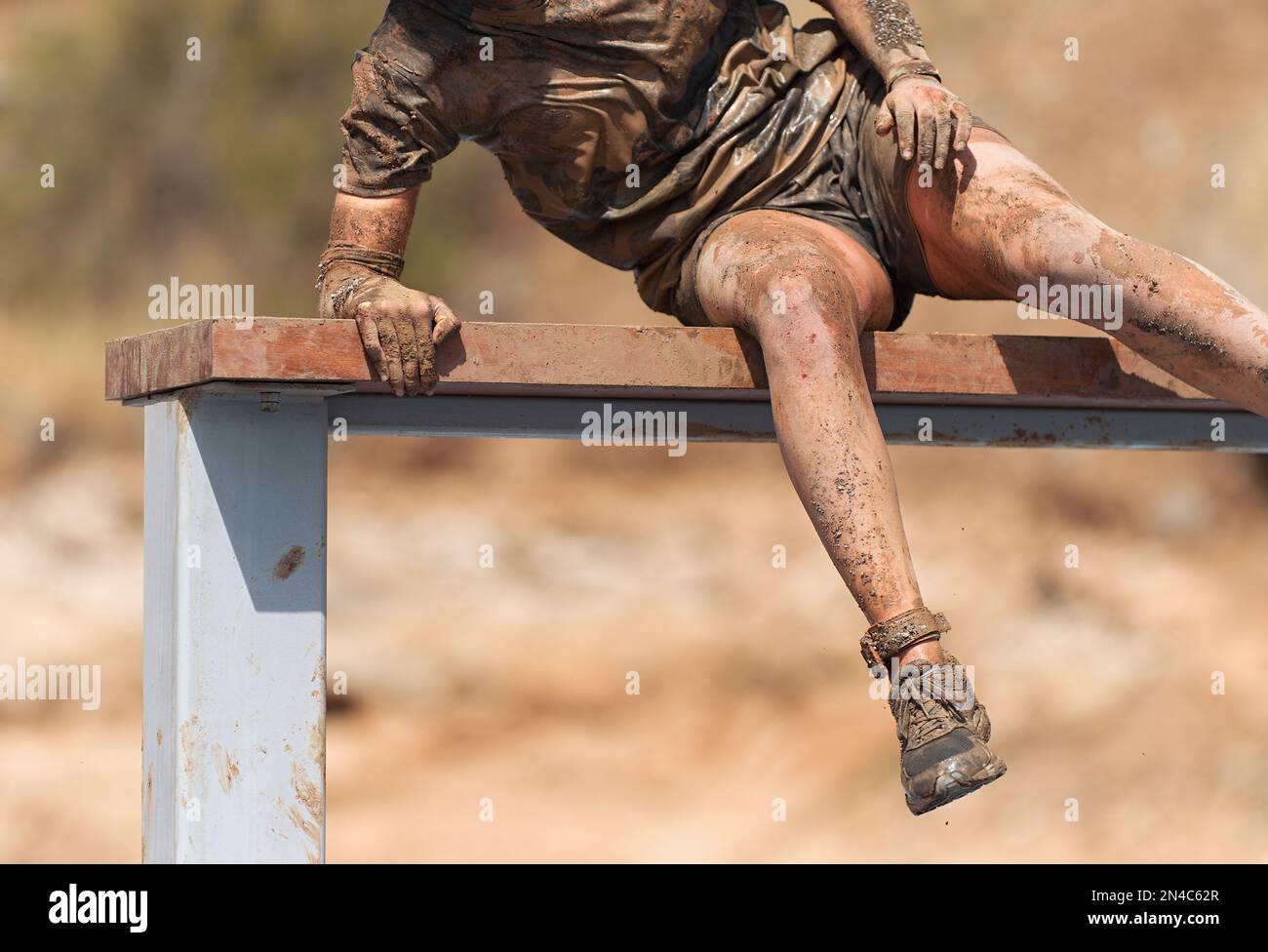 Mud race running. Running over obstacles male race participant, climbs ...