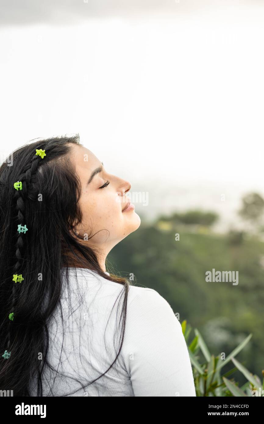 teenage Latin girl, with her head raised to the sky, breathing the