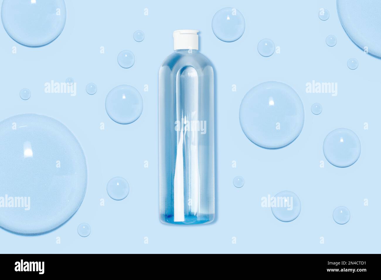 Cosmetic bottle with blue tonic, water, liquid. Large blue drops of gel, water. Nav blue background. Stock Photo