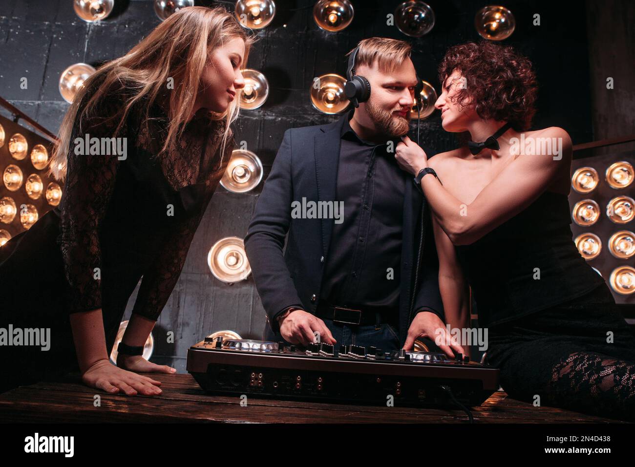 Two young girls flirt with DJ at nightclub party Stock Photo