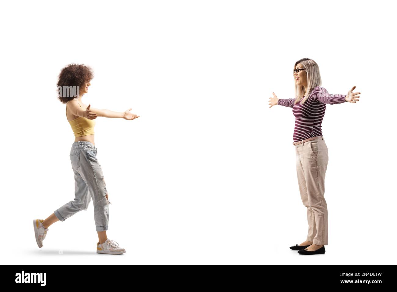 Full length profile shot of two young women meeting and greeting each other isolated on white background Stock Photo