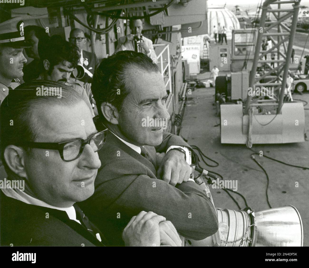 President Richard M. Nixon and Dr. Thomas O. Paine, NASA Administrator, watch Apollo 11 astronauts Neil A. Armstrong, Michael Collins and Buzz Aldrin Jr., walk from the recovery helicopter to the Mobile Quarantine Facility aboard the U.S.S. Hornet. The President later congratulated the astronauts by microphone, speaking through a window of the quarantine trailer. During the eight-day space mission, Armstrong and Aldrin explored the Moon's surface and brought back rock samples for scientists to study. Collins piloted the command module in the lunar orbit during their 22-hour stay on the moon. T Stock Photo