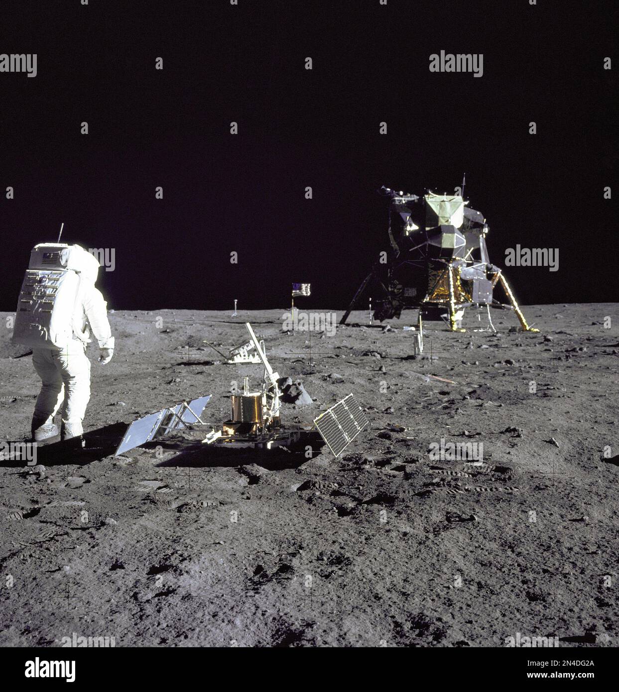 Astronaut Edwin E.'Buzz' Aldrin Jr., Lunar Module pilot, is photographed during the Apollo 11 extravehicular activity on the Moon. He has just deployed the Early Apollo Scientific Experiments Package (EASEP). In the foreground is the Passive Seismic Experiment Package (PSEP); beyond it is the Laser Ranging Retro-Reflector (LR-3); in the center background is the United States flag; in the left background is the black and white lunar surface television camera; in the far right background is the Lunar Module 'Eagle'. Astronaut Neil A. Armstrong, commander, took this photograph with a 70mm lunar s Stock Photo