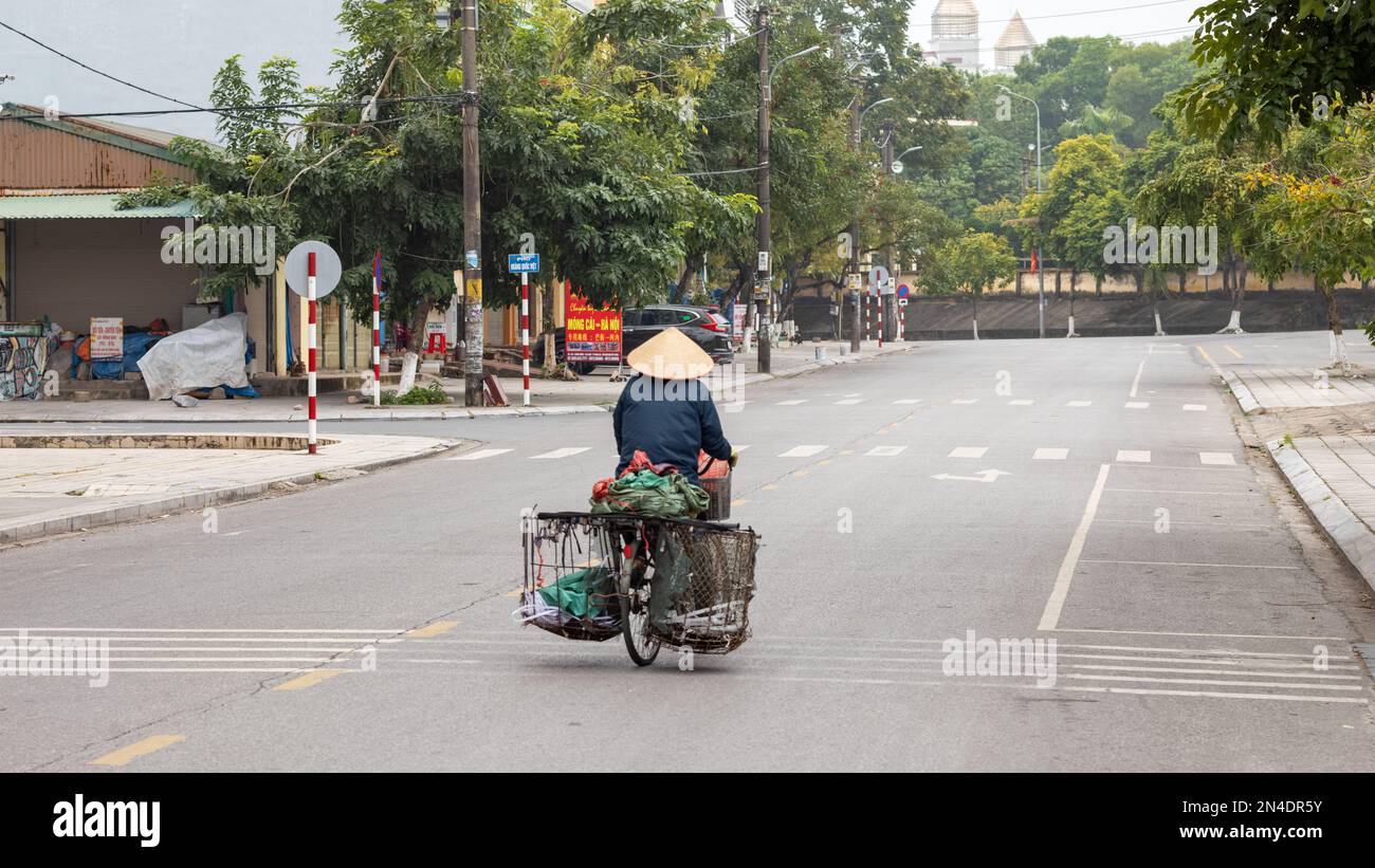 An elderly man pedals his bicycle with old wire baskets attached in Mong Cai, Vietnam, on the border with China. Stock Photo
